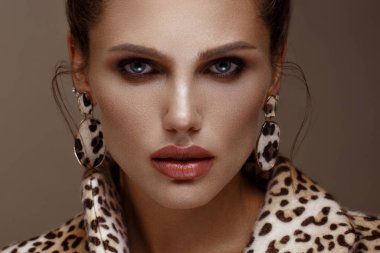 Klasik dumanlı makyaj ve şık bir saç modeli ile leopar ceket ve küpe, güzel seksi kadın. Güzellik yüzü.