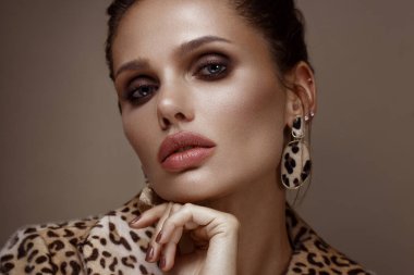 Klasik dumanlı makyaj ve şık bir saç modeli ile leopar ceket ve küpe, güzel seksi kadın. Güzellik yüzü.
