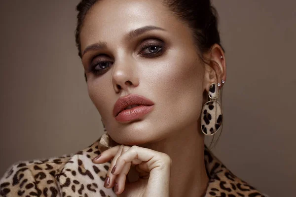 Красива сексуальна жінка в леопардовому пальто і сережки, з класичним димчастим макіяжем і модною зачіскою. Обличчя краси . — стокове фото