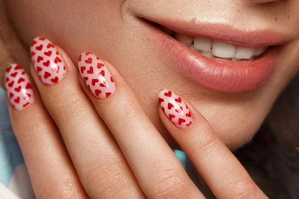 Chica bonita con rizos peinado, maquillaje clásico, pecas, labios desnudos y diseño de manicura con corazones. Cara de belleza. La imagen para el Día de San Valentín —  Fotos de Stock