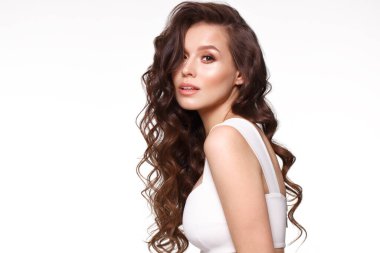 Beautiful young girl in white dress with natural make-up, hair curls and smile.