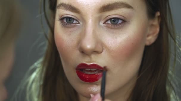 Maquiagem artista pinta os lábios do belo modelo. O processo de aplicação de maquiagem . — Vídeo de Stock
