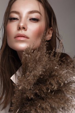 Beautiful woman with classic nude make-up, light hairstyle and dry flowers. Beauty face.