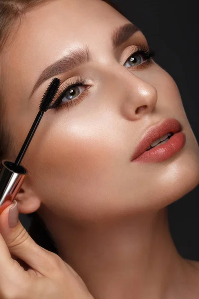 Beautiful girl with sexy lips and classic makeup with cosmetic mascara brush in hand. Beauty face. — Stock Photo, Image