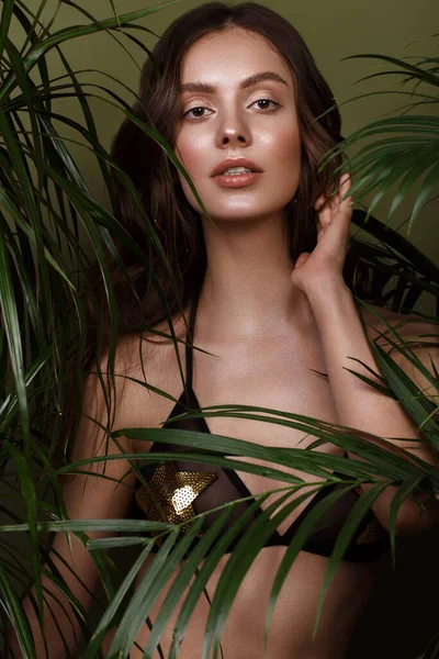 Beautiful sexy woman in a bikini posing in the middle of green plants. Summer look. Beauty face — Stock fotografie