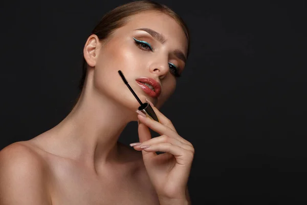 Schöne Mädchen mit sexy Lippen und klassischem Make-up mit kosmetischen Mascara-Pinsel in der Hand. Schönheitsgesicht. — Stockfoto