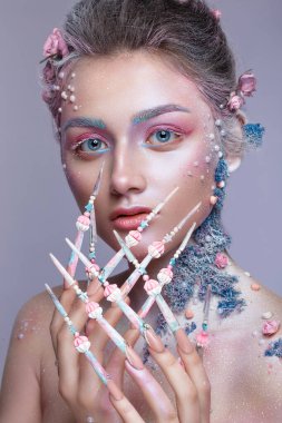 Sanat makyajlı ve uzun tırnaklı tatlı bir peri suretinde güzel bir kız. Yaratıcı manikür.