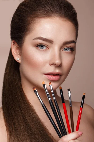 Beautiful young girl with natural nude make-up with cosmetic tools in hands. Beauty face. — Stock Photo, Image