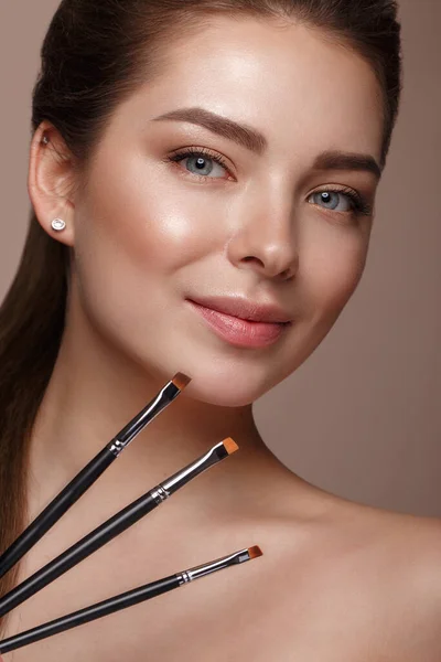 Mooi jong meisje met natuurlijke naakte make-up met cosmetisch gereedschap in de handen. Schoonheidsgezicht. — Stockfoto