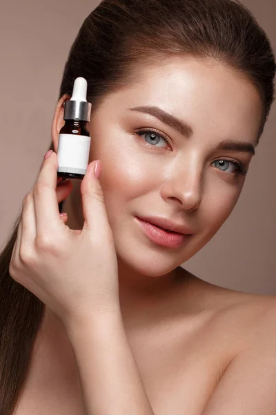 Hermosa joven con maquillaje natural desnudo con cosméticos en las manos. Cara de belleza . — Foto de Stock