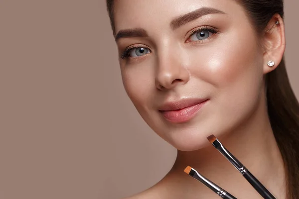 Mooi jong meisje met natuurlijke naakte make-up met cosmetisch gereedschap in de handen. Schoonheidsgezicht. — Stockfoto