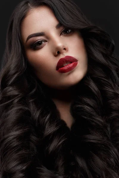Piękny model brunetka: loki, klasyczny makijaż i czerwone usta. Piękna twarz.. — Zdjęcie stockowe