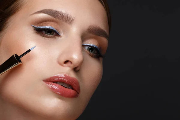 Beautiful girl with sexy lips and classic makeup with cosmetic blue eyeliner in hand. Beauty face. — Stok fotoğraf