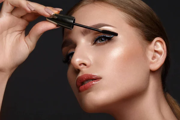 Beautiful girl with sexy lips and classic makeup with cosmetic mascara brush in hand. Beauty face. — Stock Photo, Image