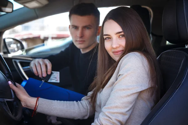 Yeni arabadaki mutlu kız, genç bir adamdan ehliyet ve anahtar aldı.. — Stok fotoğraf