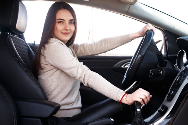 Young beautiful happy woman sitting at the wheel new car.