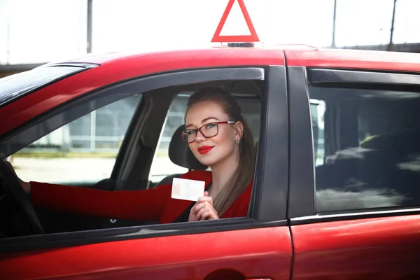 Radosna dziewczyna prowadząca samochód treningowy z kartą kierowcy w rękach — Zdjęcie stockowe