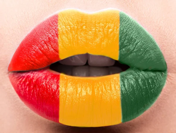 Los labios femeninos se cierran con una bandera de Guinea. Amarillo, verde, rojo . — Foto de Stock