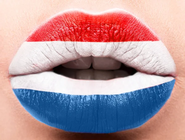 Kvinnliga läppar på nära håll med en bild flagga av Nederländerna. Blå, vit, röd. — Stockfoto