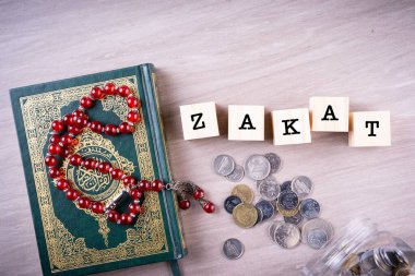 Zakat concept: Quran and tasbih with jar full of coins. The wordings on the book is arabic words which means Holy Quran clipart