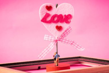 Pembe arka planda minyatür çift