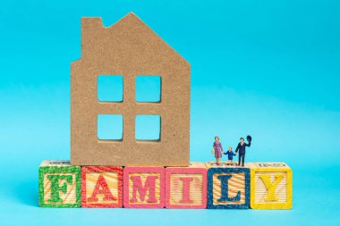 Mutlu Aile kavramı. Minyatür aileler ve çocukların heykelleri ahşap evle ahşap bloklarda ailevi ifadeler.