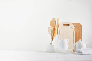 Mutfak arka planında kaşık, çaydanlık ve beyaz arka planda fincanlar var. Ev mutfağı kavramı için boş alan.