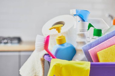 Cleaning products: sponge, bottle , glove, brush, spray on table and gray kitchen background, close up