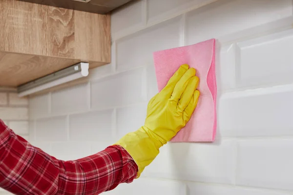 Woman cleaning kitchen tiles with pink cloth and gloves. Household equipment, tidying up, cleaning service concept. — Stock fotografie