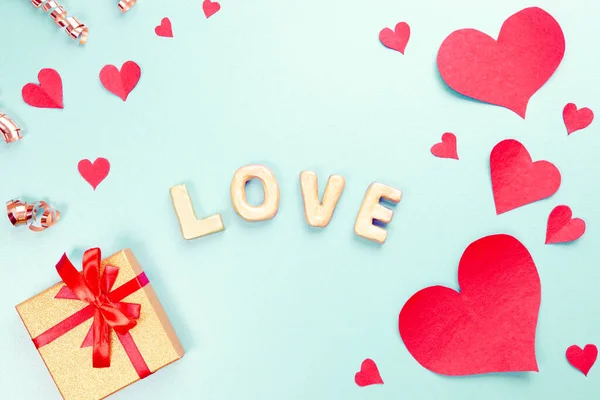 Word Love with gold Gifts, red paper hearts, confetti. Sweet holiday background, small hearts. — ストック写真