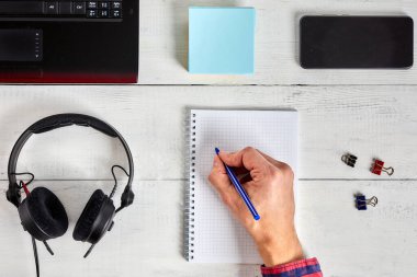 Beyaz ahşap masaya bir adamın el yazısı. Çalışma yeri ve planlama konsepti, üst görünüm.