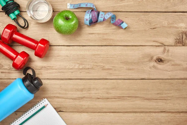 Healthy lifestyle, lose weight and sport concept. Top view of athlete's equipment: dumbbell, sport water bottles, blank notebook, jump rope on natural wooden background. Space for text. — Stock Image Healthy Lifestyle Lose Weight Sport Concept Top View Athlete Equipment Stock Picture