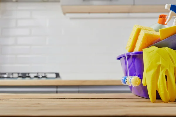 Cleaning supplies : sponge, bottle , glove, spray on table and gray kitchen background