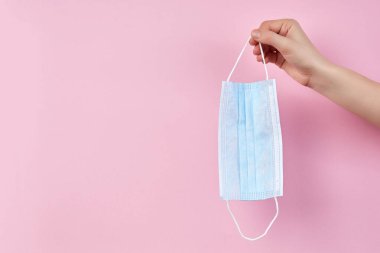 Pembe arka planda el ele tutuşan tıbbi koruyucu maske
