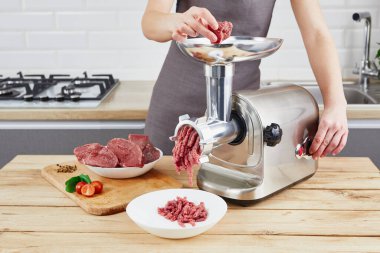 Etleri kıyma makinesi vasıtasıyla hazırlama süreci. Kadın eli mutfakta et helikopteri kullanıyor..