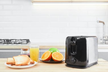 Tabaklı tost makinesi ve mutfak masasında taze meyve suyu ile kızarmış ekmek.