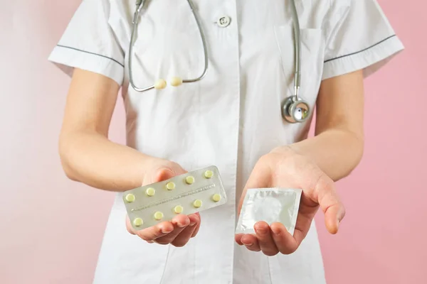 Female doctor holding condom for aids prevention and birth control pills. Contraceptives in hands for safe sex — Zdjęcie stockowe