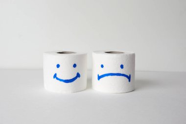 Tuvalet kağıdı yuvarlanıyor, beyaz arka planda mutlu ve üzgün bir gülümseme var.