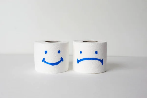 Toilet paper roll with happy and sad smiles on a white background