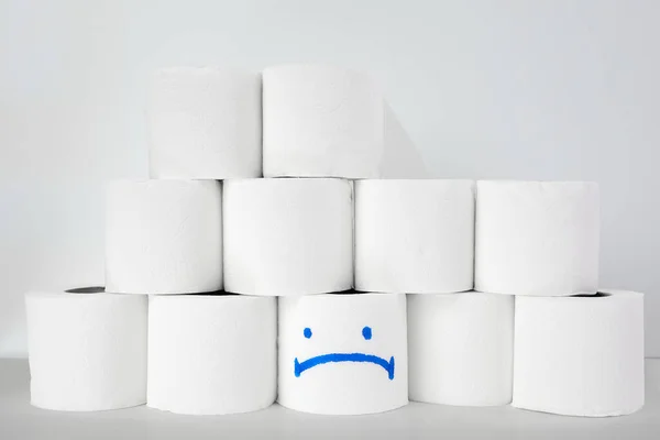 Toilet paper roll with sad smile on a white background. Covid-19 and coronavirus panic concept