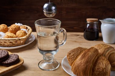 Masaya konmuş sıcak çay, sabahları kahvaltı, çay süzgeciyle kahvaltı ve ahşap masada tatlı.