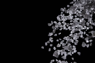 Siyah arka plana beyaz deniz tuzu döküldü. Siyah zemin üzerinde kristal çakıl taşları