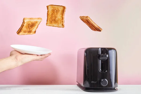 Tostlar modern tost makinesinden fırladı. Havalandırma yiyeceği ve yemek. Pembe arka planda nefis bir sabah kahvaltısı konsepti.