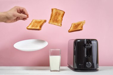 Tostlar modern tost makinesinden fırladı. Bir bardak sütün yanında. Havalandırma yiyeceği ve yemek. Pembe arka planda nefis bir sabah kahvaltısı konsepti.