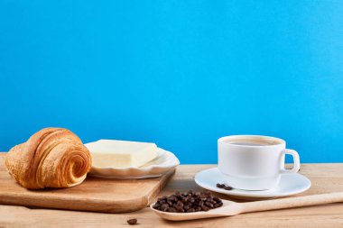 Kahve kahvaltısı, kruvasan, tereyağı ve bir fincan sade kahve, meşe ağacından masa..