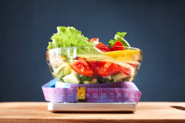 diyet, sağlıklı beslenme, yiyecek ve kilo kaybı konsepti mutfak ölçeğinde salata ile ölçüm bandı. Kapat.
