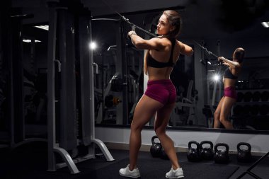 Jimnastik salonunda simülatörde spor yapan kız elleriyle egzersiz yapıyor. Spor motivasyonu kavramı.
