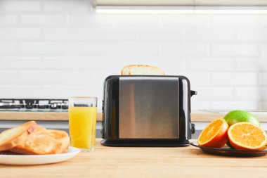Tabaklı tost makinesi ve mutfak masasında taze meyve suyu ile kızarmış ekmek.
