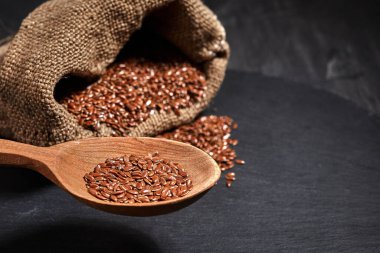 Keten tohumu ve üzerinde bez bir çanta olan tahta bir kaşık. Sağlıklı yiyecek ve içecek konsepti. Üst Manzara. Kapat.