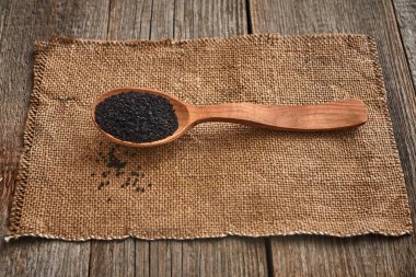 Siyah kimyon tohumları ve ahşap bir masanın üzerinde tuval olan tahta bir kaşık. Sağlıklı vejetaryen, organik gıda konsepti. Kapat.